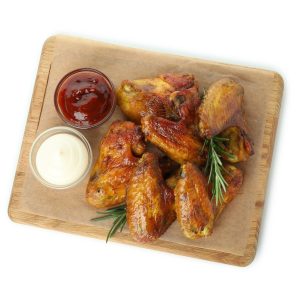 Board with chicken wings and sauces isolated on white background