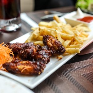 side view bbq chicken wings with fries and carrots on a plate