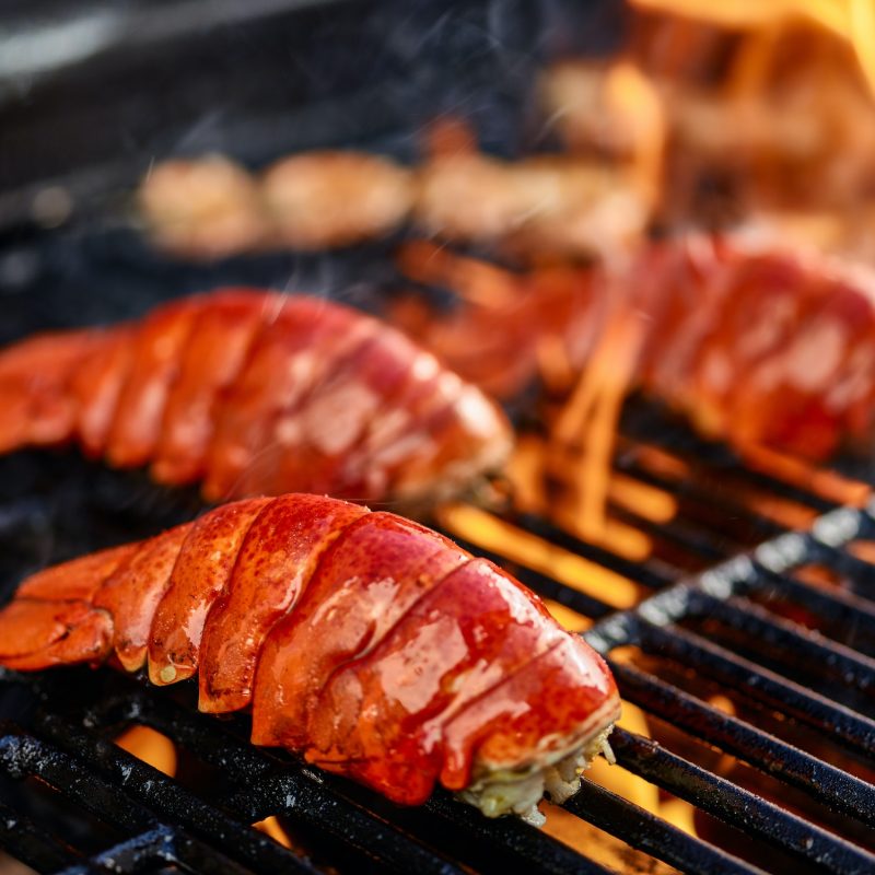 Delicious and juicy lobster tails grilling on an open flame.